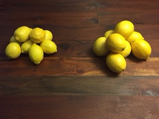 Pile of organic lemons next to a pile of conventional lemons.